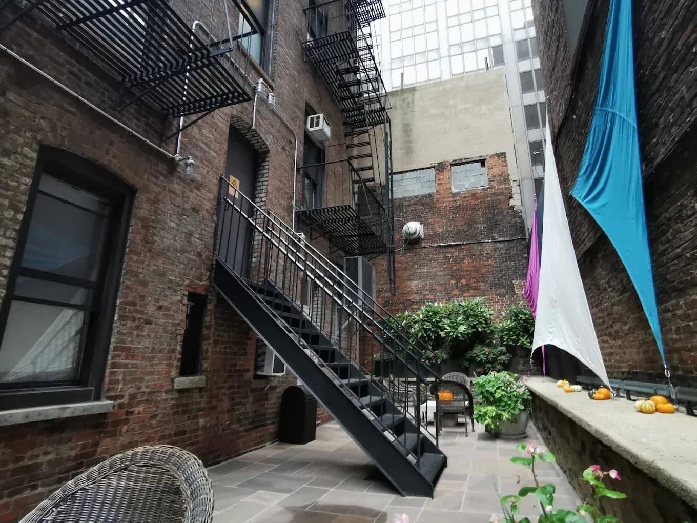 The rear courtyard at Seton Residence, with planted beds, shade sails and the building's fire escape overhead