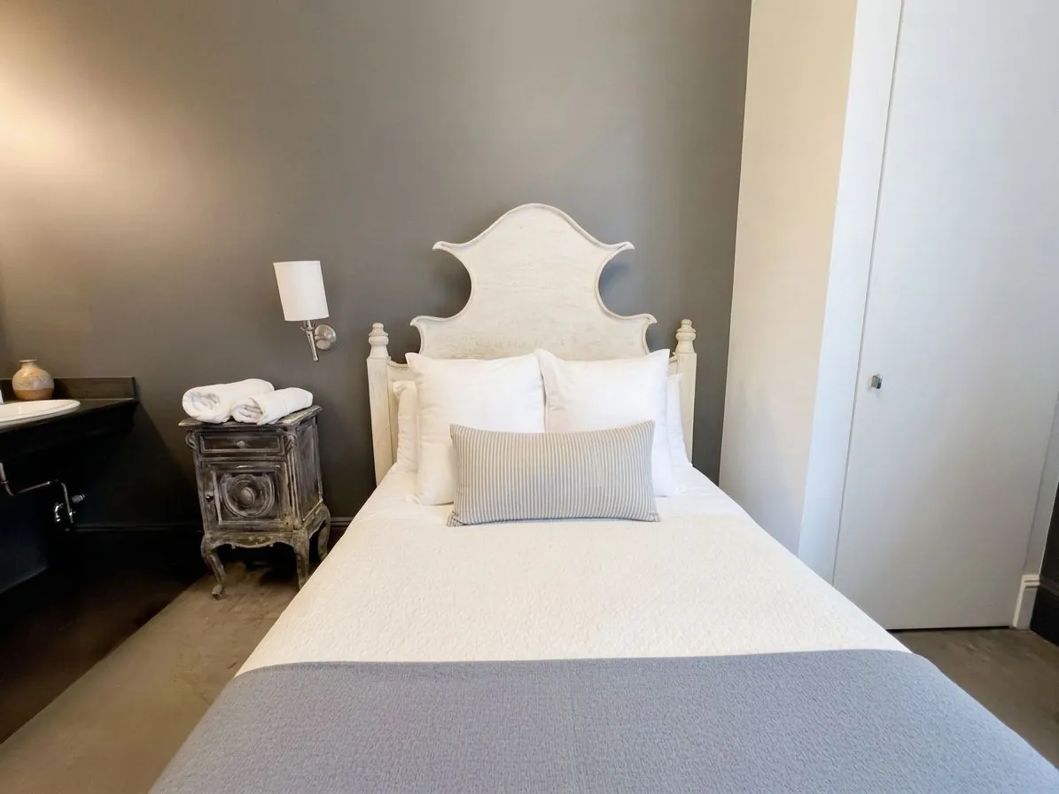 A Deluxe Room in grey and white with a nightstand and reading lamp