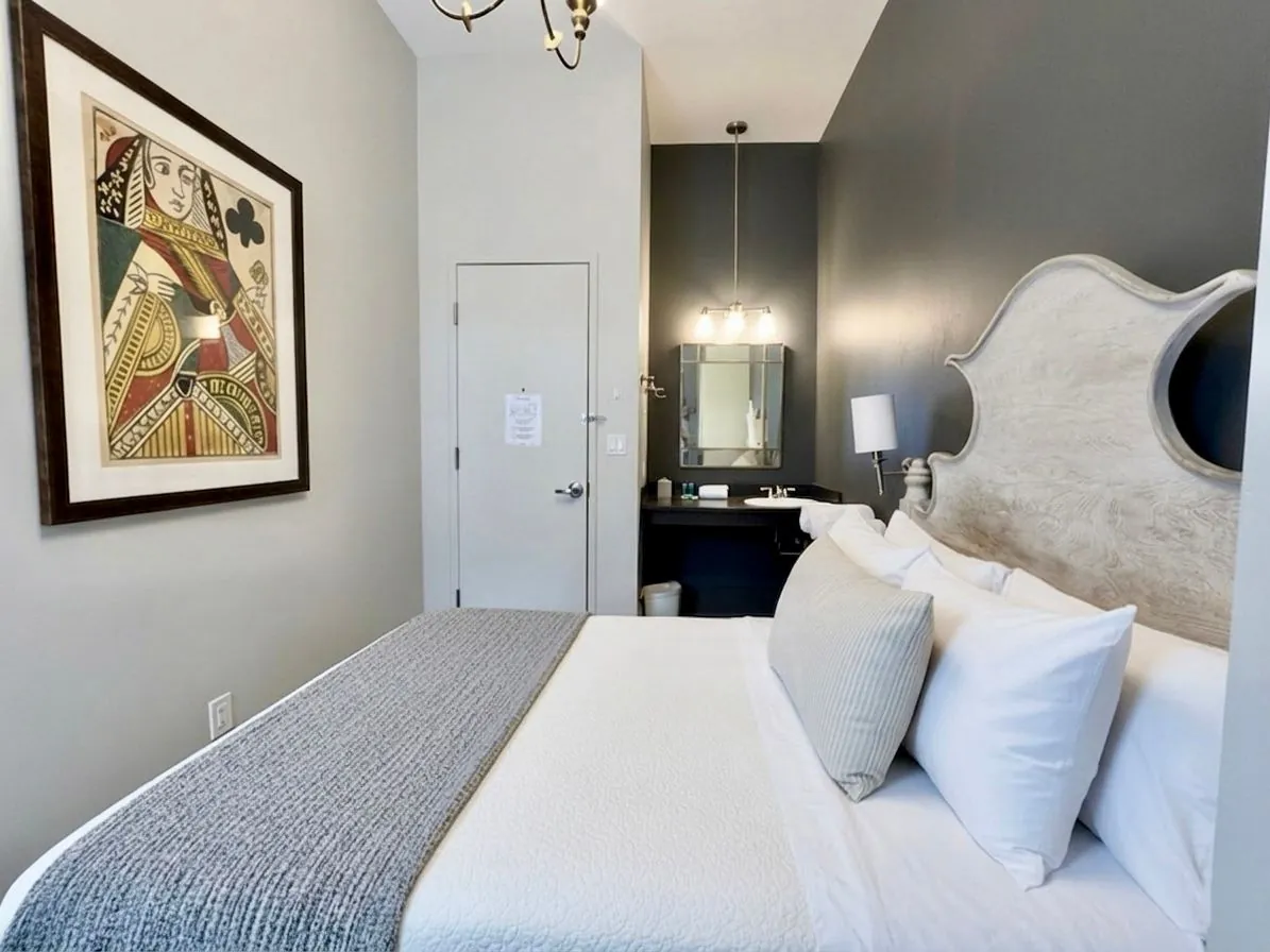 A Deluxe Room with framed artwork, a dressing mirror and a dark accent wall