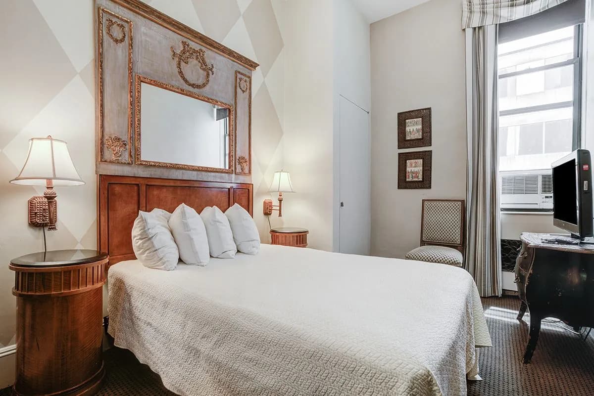 A Deluxe Room with a full bed, mirrored console and tall window