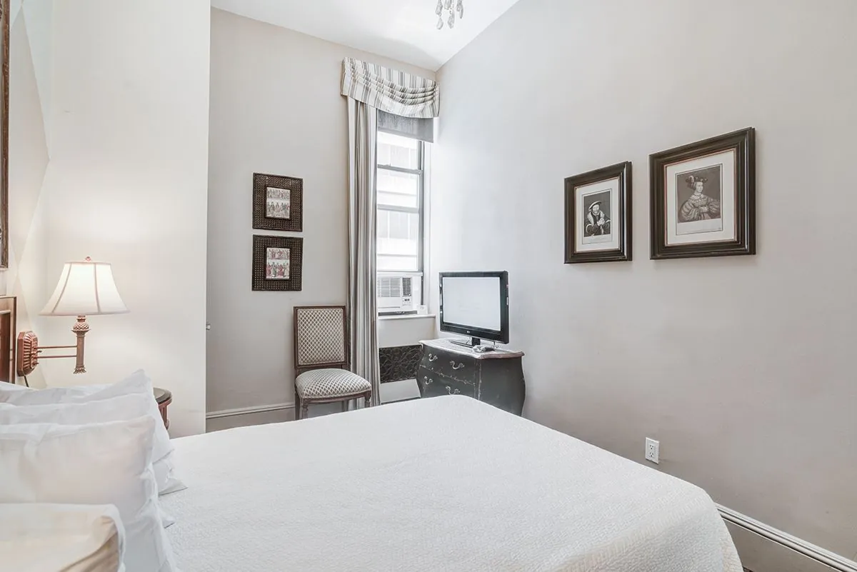 A Deluxe Room with a writing desk and framed prints above the bed