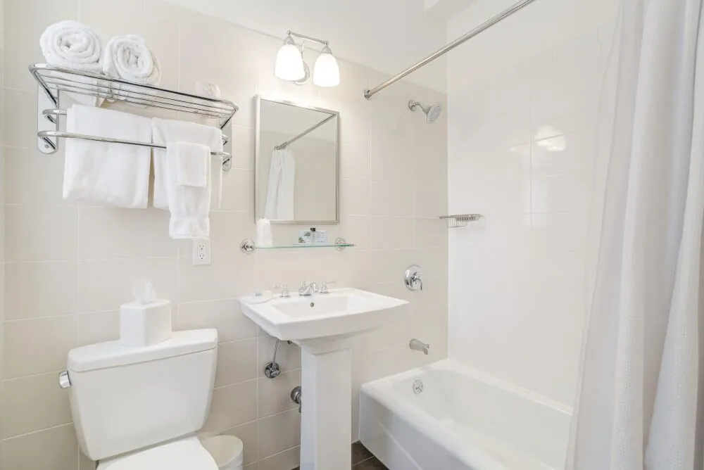 A shared bathroom with a pedestal basin, bathtub and folded towels