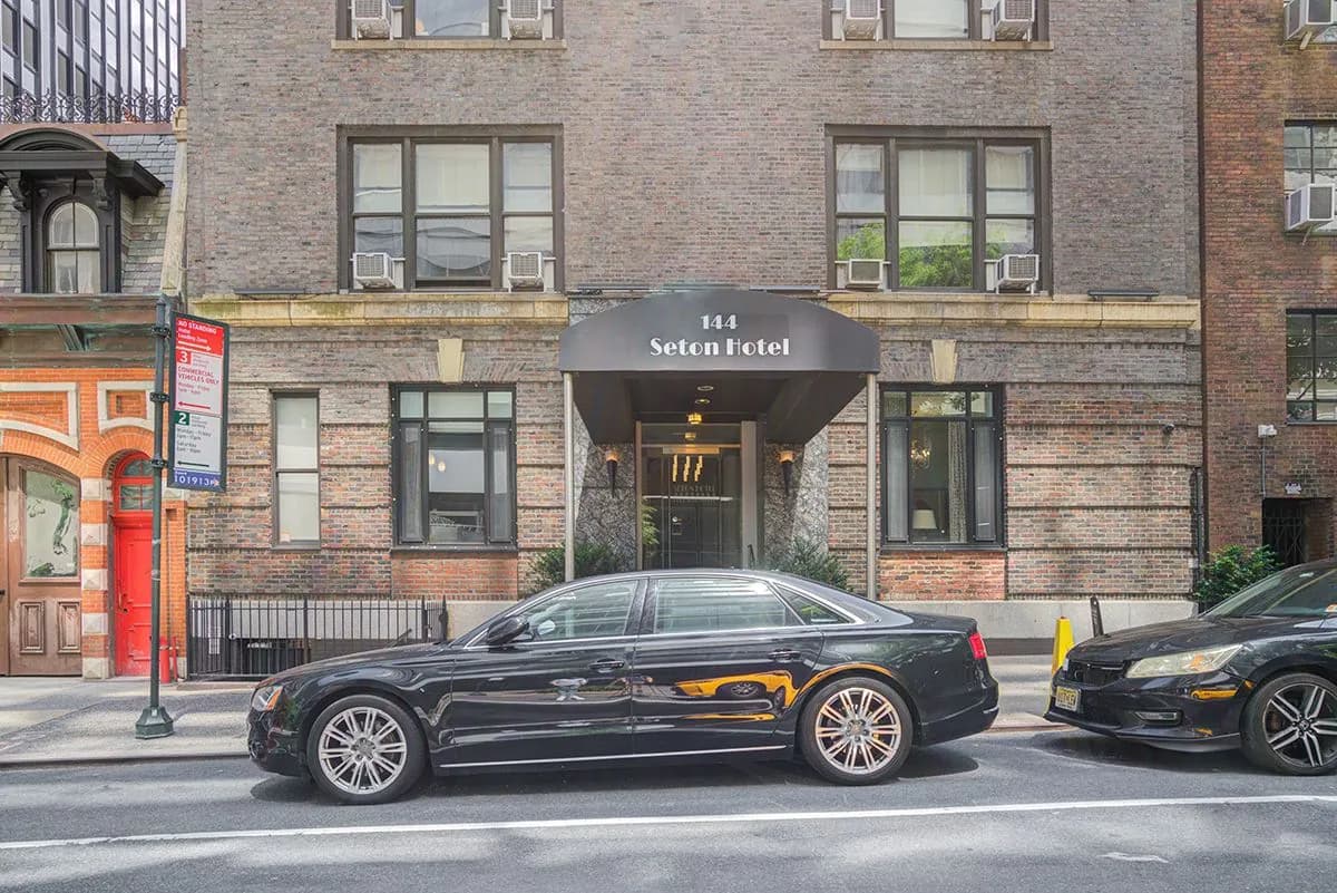 144 East 40th Street from the sidewalk, cars parked along the block in front of the entrance canopy