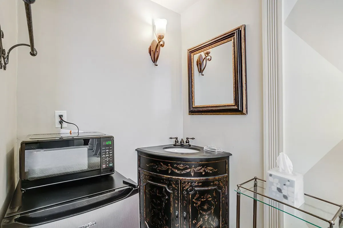 The in-room pantry counter with a microwave and kettle beside a framed mirror