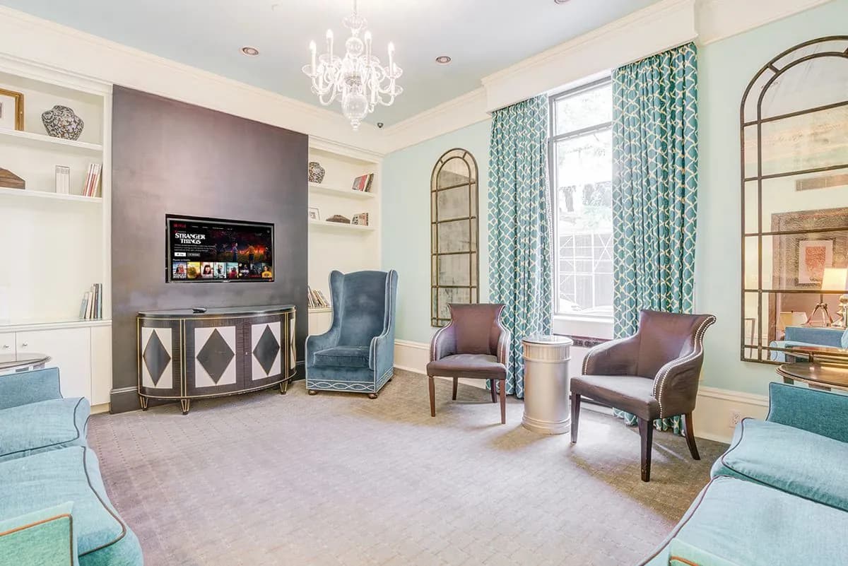 The residents' lounge: a fireplace, upholstered armchairs and tall arched windows