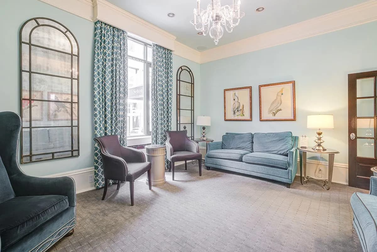 A seating area in the lounge with a sofa, arched mirrors and a chandelier