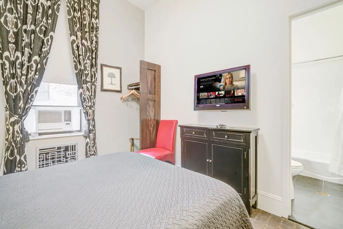 A Studio Basic with a dresser, wall-mounted television and a red accent chair