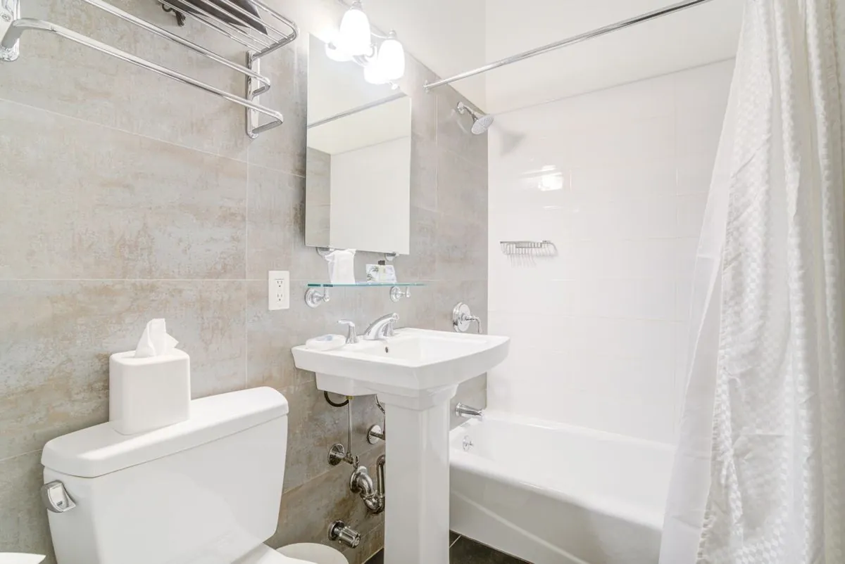 An en-suite bathroom with a pedestal basin, bathtub and shower